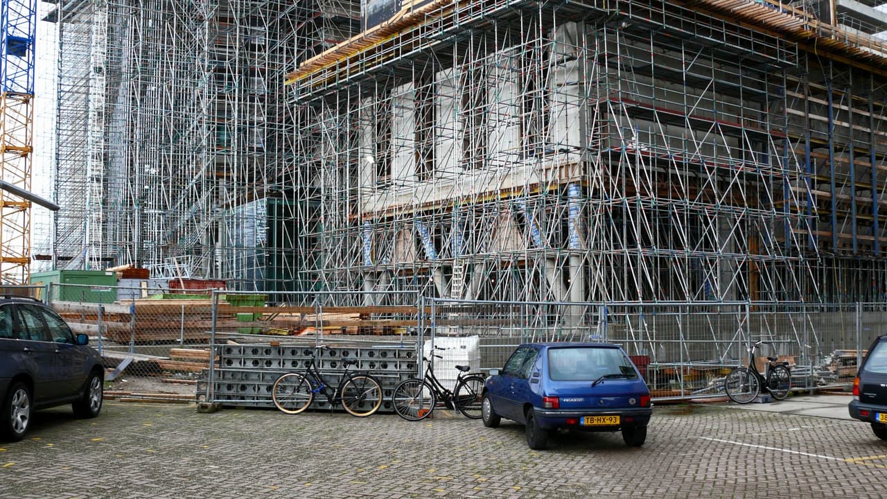 Een gebouw in aanbouw, helemaal ingepakt in steigers.