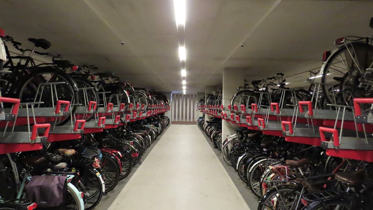 Lange rijen fietsen in een inpandige fietsenstalling.