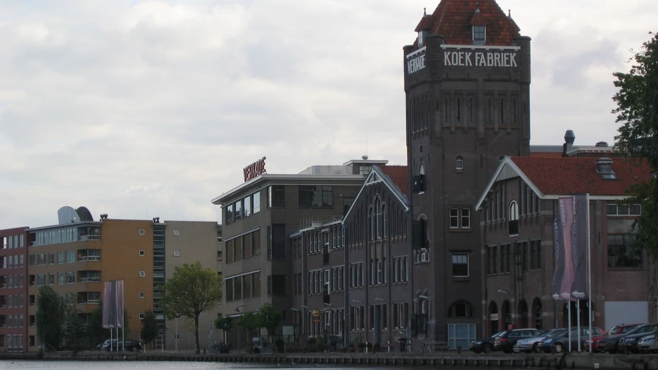 Een oud bakstenen fabrieksgebouw met een schoorsteen en de tekst Koekfabriek op de gevel.