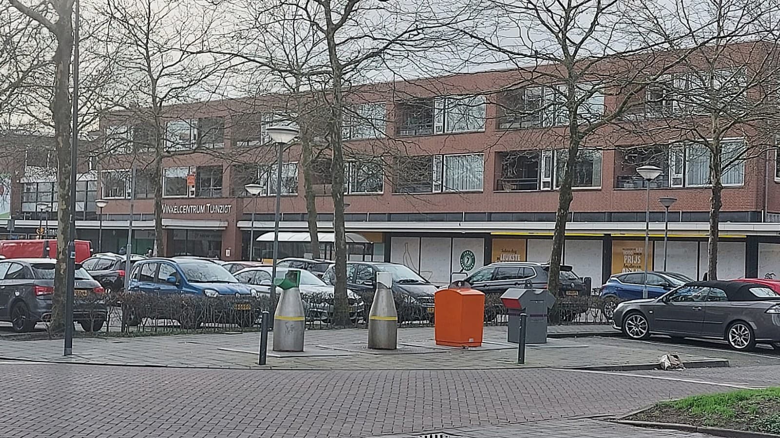 Een straat in de Bredase wijk Tuinzigt met bakstenen woningen, jonge bomen en geparkeerde auto's.